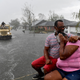 People react as a sudden rain shower soaks them with water while riding out of a flooded neighborhood in a volunteer high water truck assisting people evacuating from homes after neighborhoods flooded in LaPlace, Louisiana on August 30, 2021 in the aftermath of Hurricane Ida. -